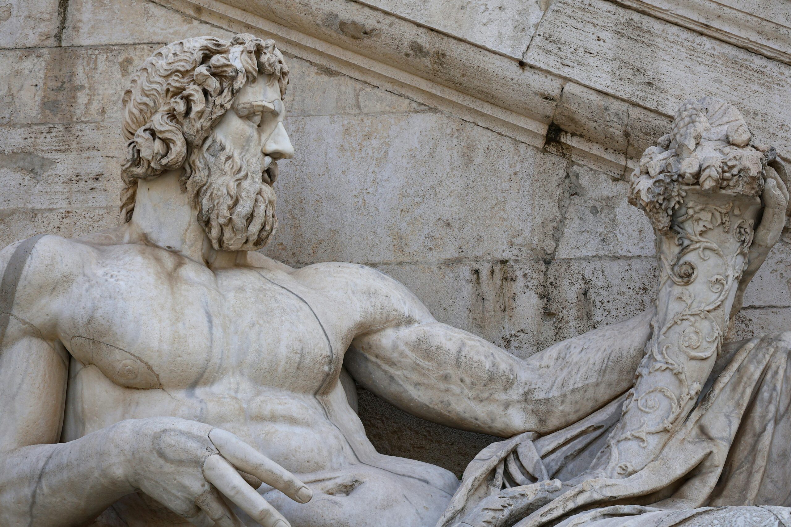 Detailed Renaissance marble statue of a god in Rome, showcasing intricate carvings.