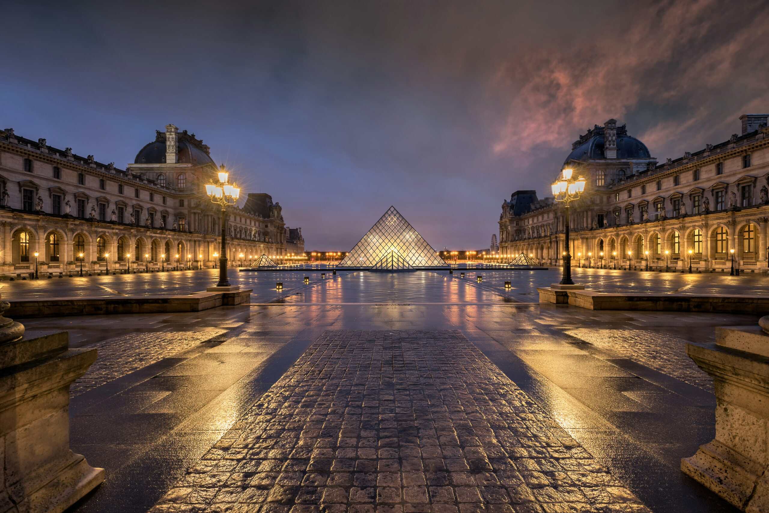 Louvre Museum Paris glass pyramid courtyard at sunset