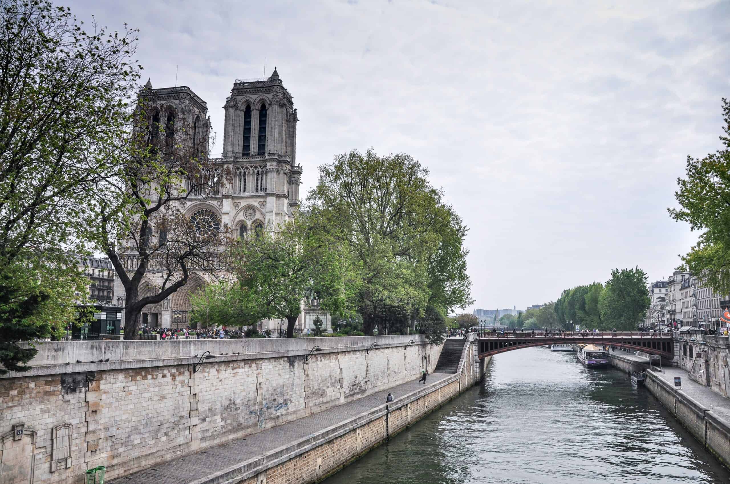 Notre-Dame Cathedral Paris view from the Seine river with bridge and trees