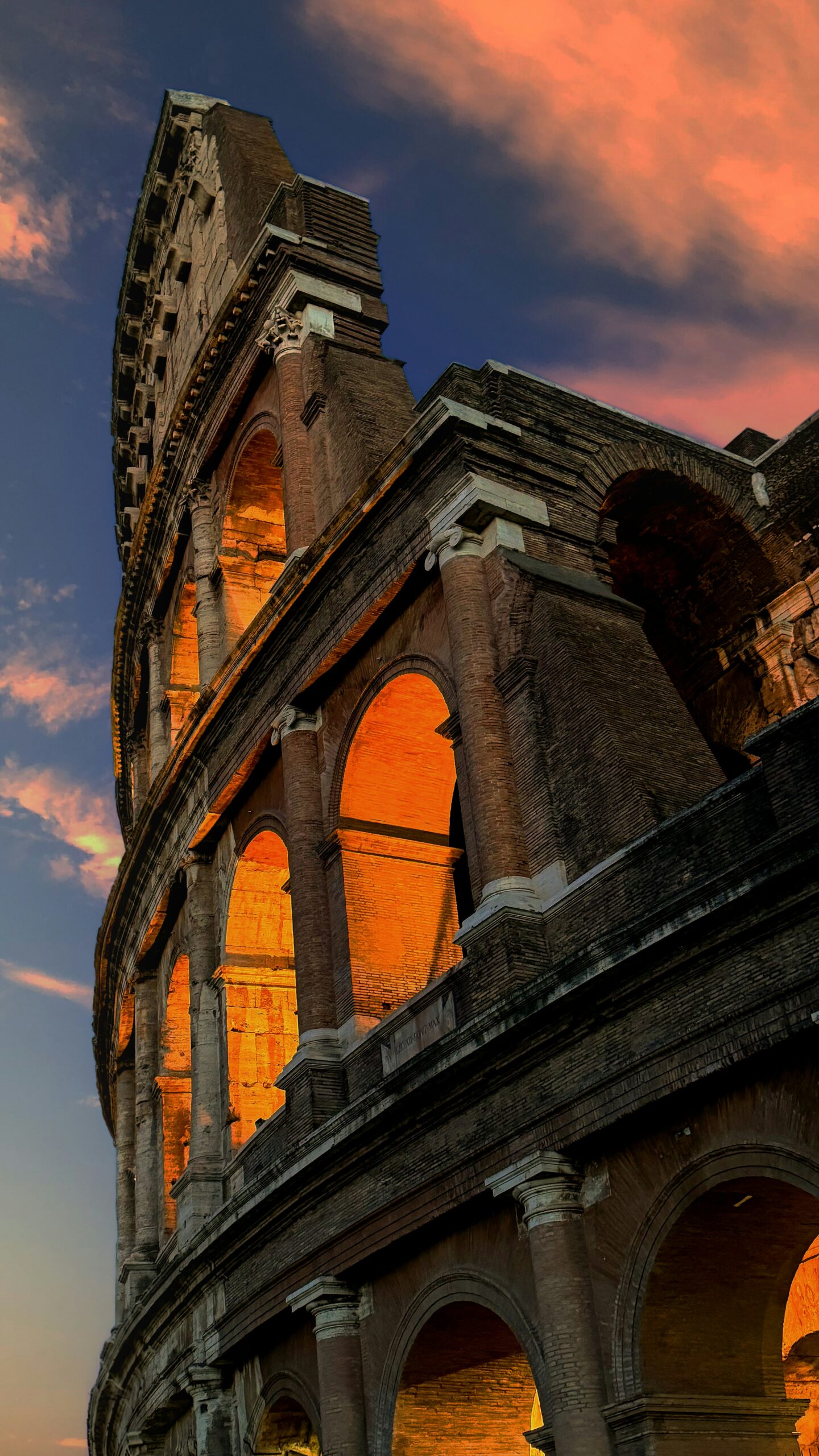 View from the Colosseum in Rome at sunset with glowing arches and dramatic sky