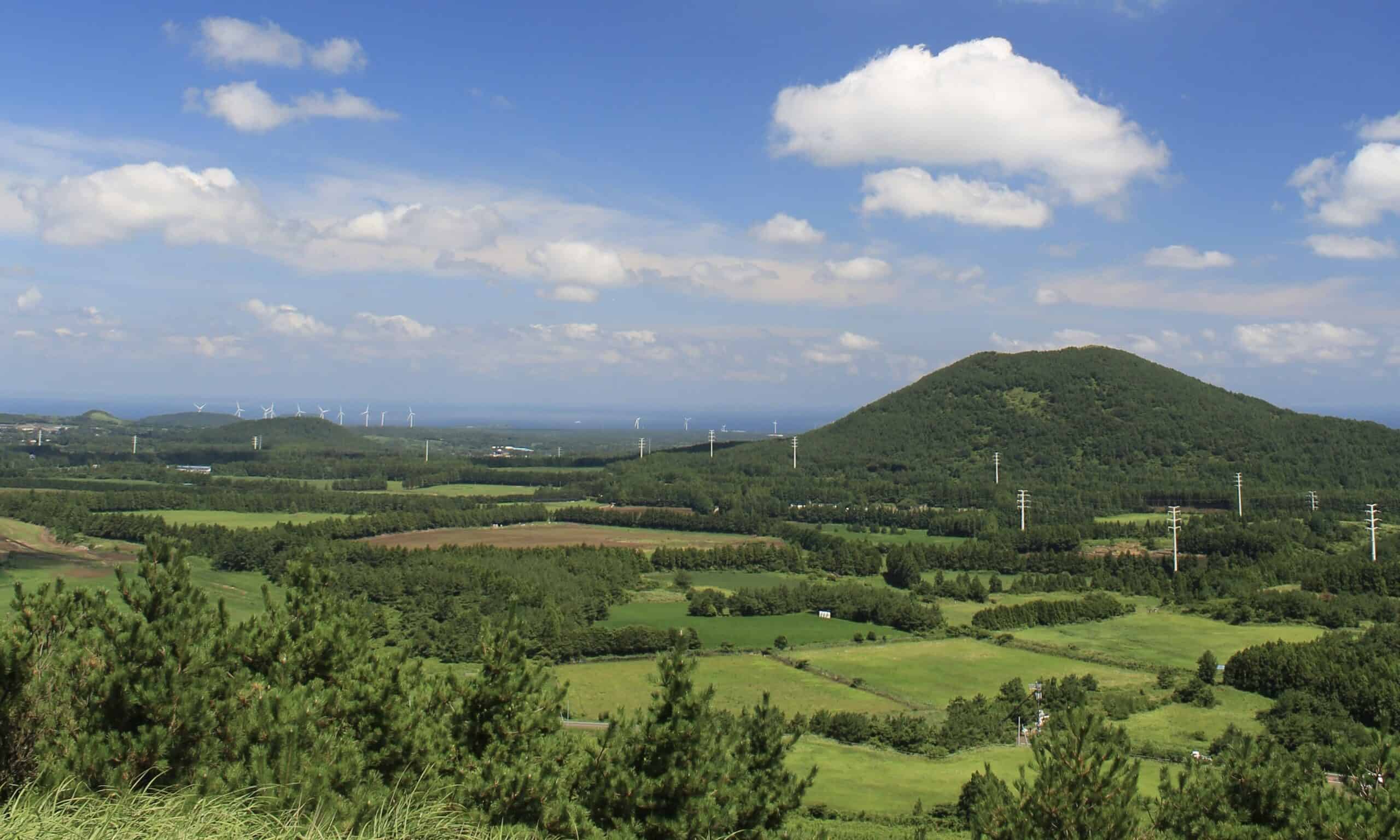 Saebyeol Oreum in Jeju volcanic cone rising above green fields and western Jeju countryside landscape