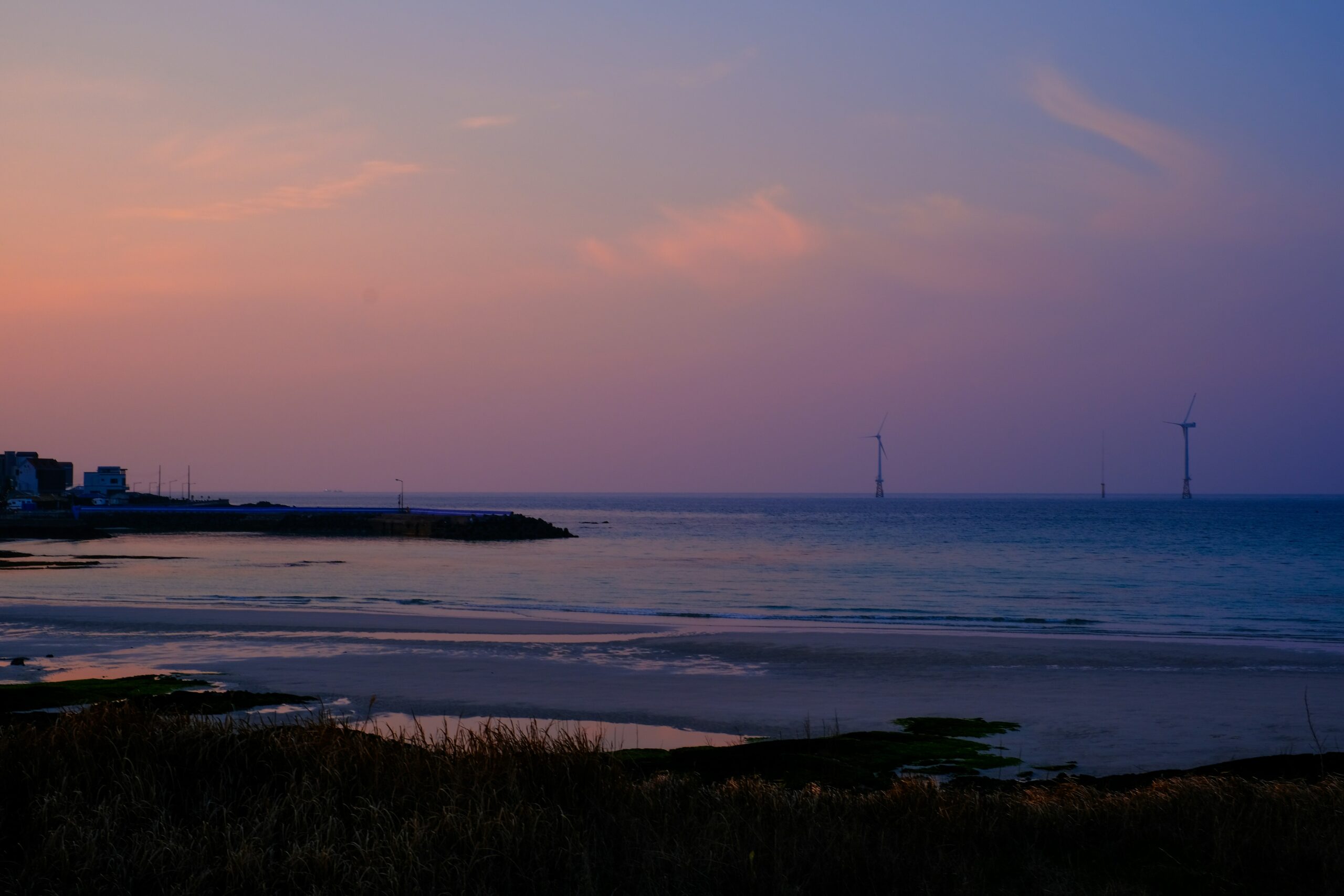 Sunset at Hamdeok Beach Jeju with calm turquoise water and a pastel sky over the shoreline
