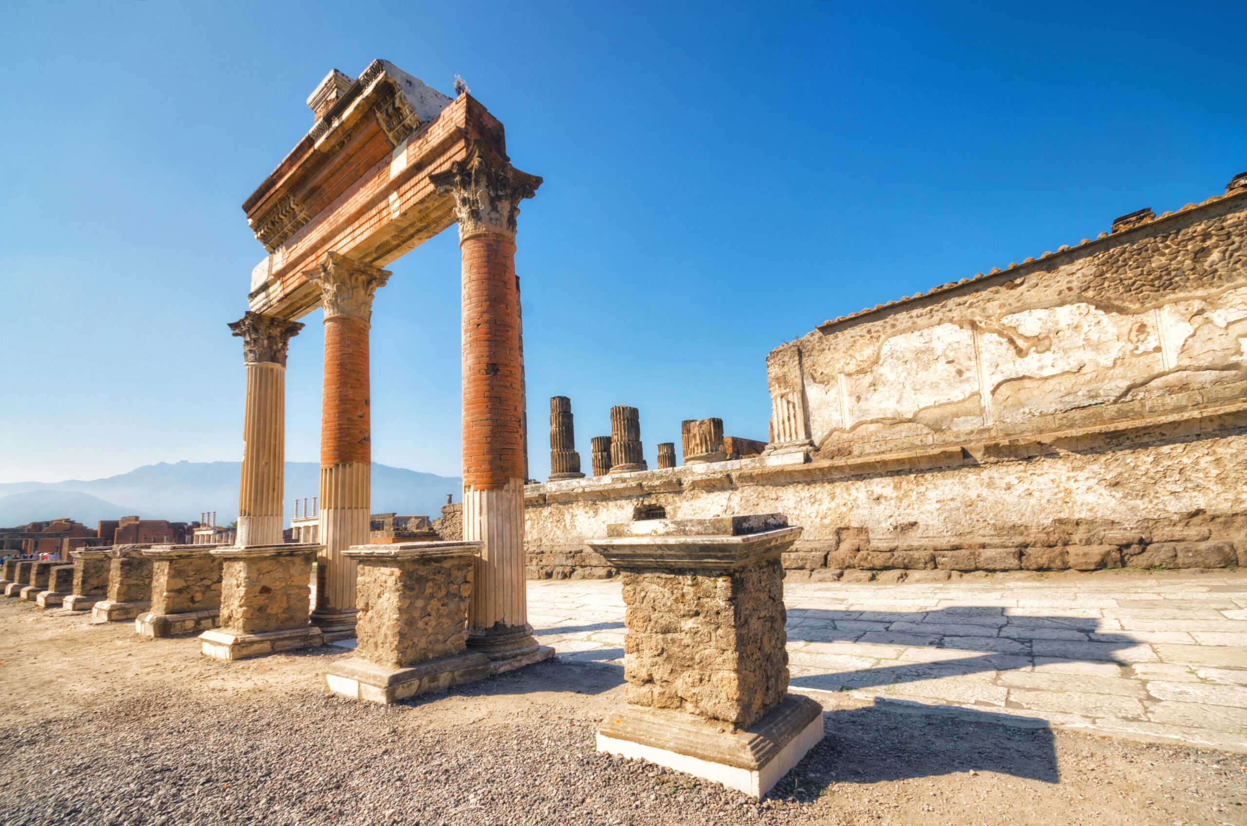 Pompeii Archaeological Park ruins with ancient Roman columns and Mount Vesuvius in the background