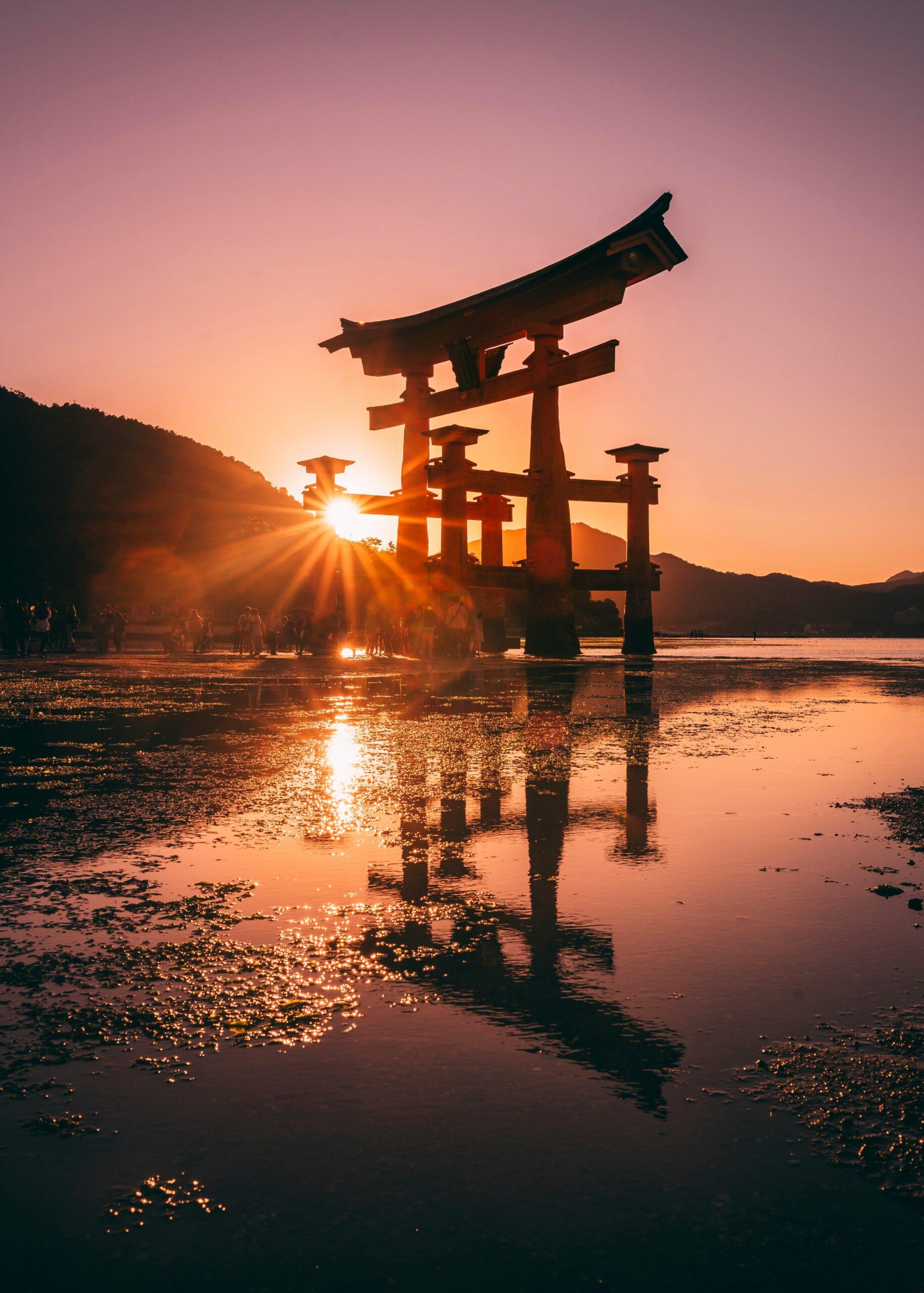 Itsukushima Shrine floating torii gate at sunset in Miyajima Hiroshima Japan with reflection on water
