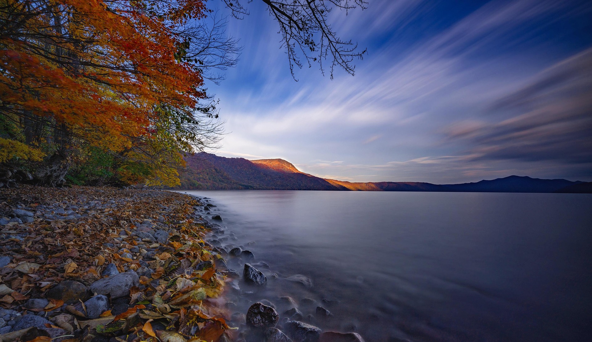Lake Towada autumn shoreline with colorful foliage and calm water in northern Japan