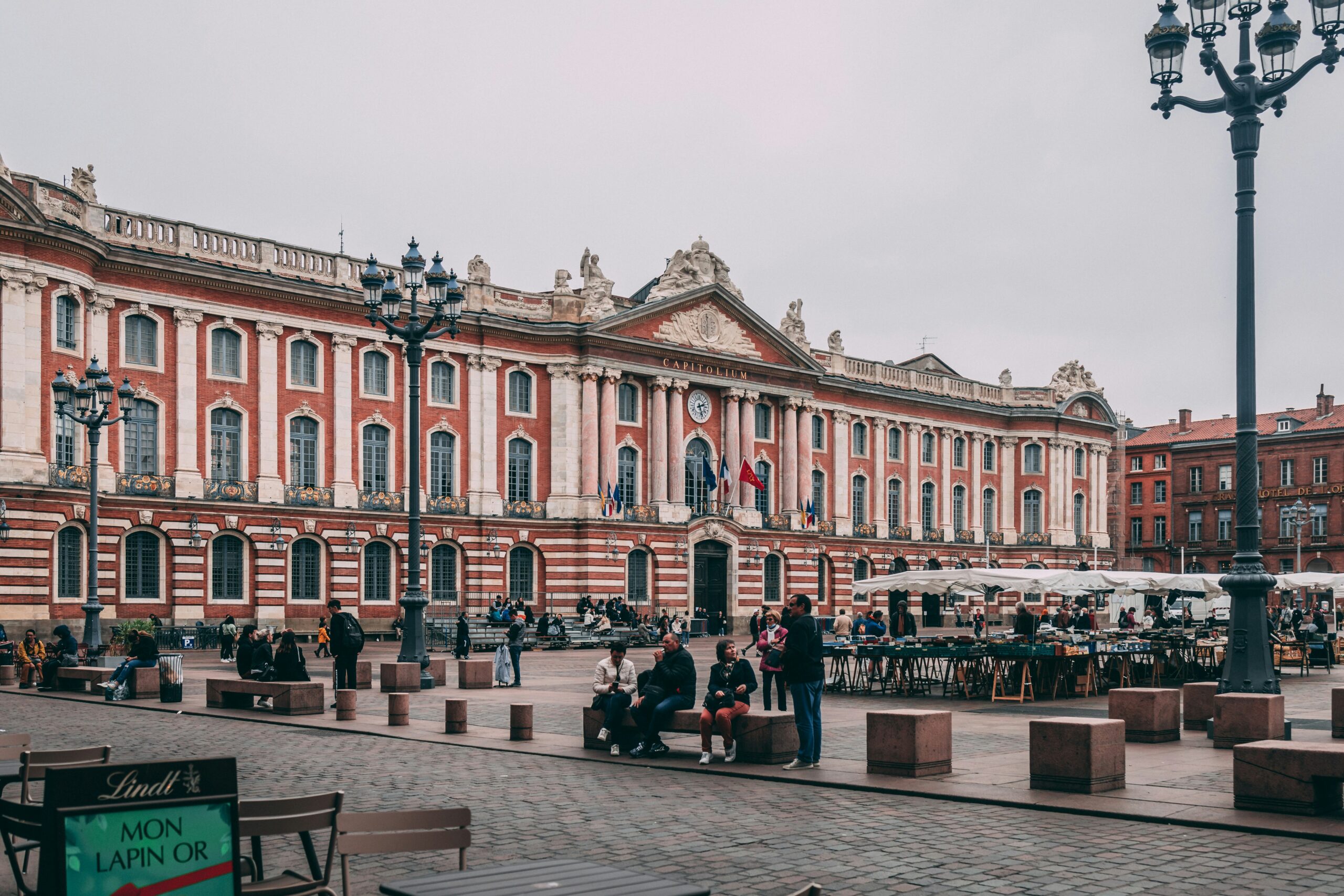 Place du Capitole square in Toulouse with people and pink brick buildings
