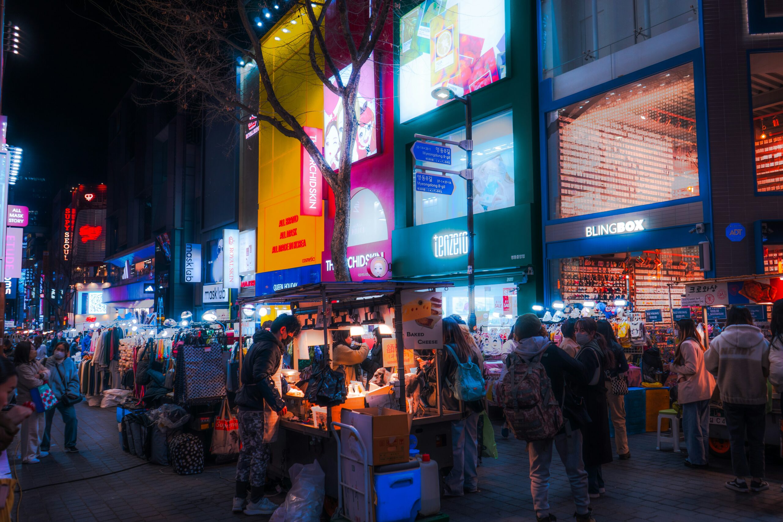 Street food stalls and neon lights in Myeongdong Shopping Street at night in Seoul