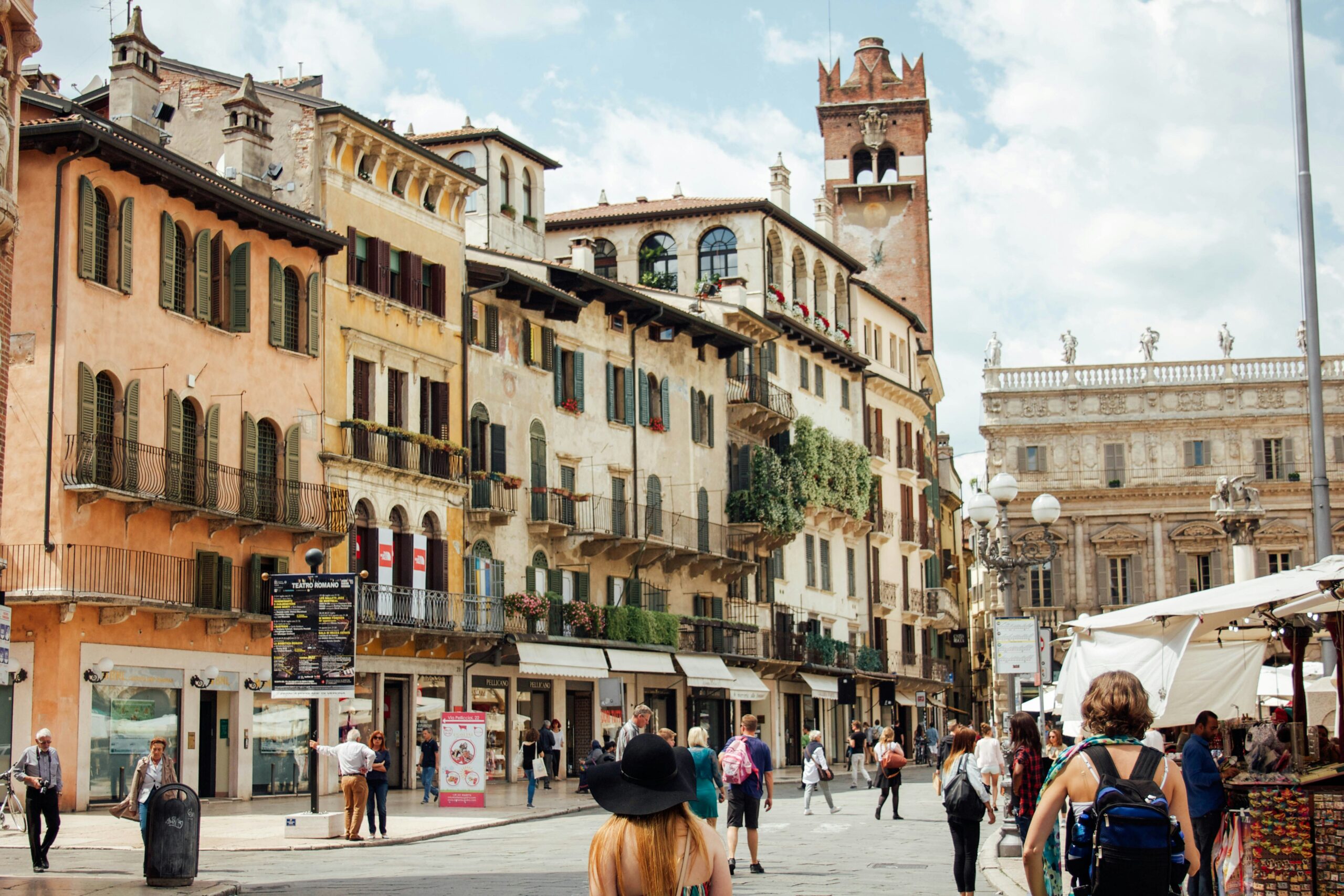 Piazza delle Erbe Verona street view with historic buildings and walking tourists Italy