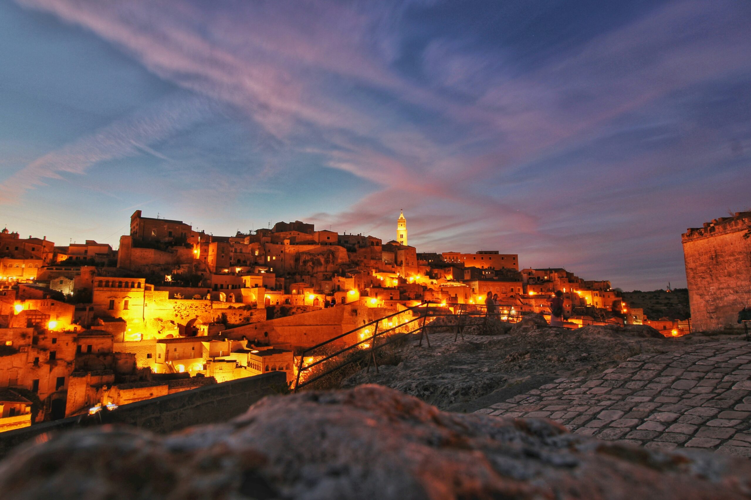 Matera Sassi at night glowing with lights over ancient cave city landscape in Italy
