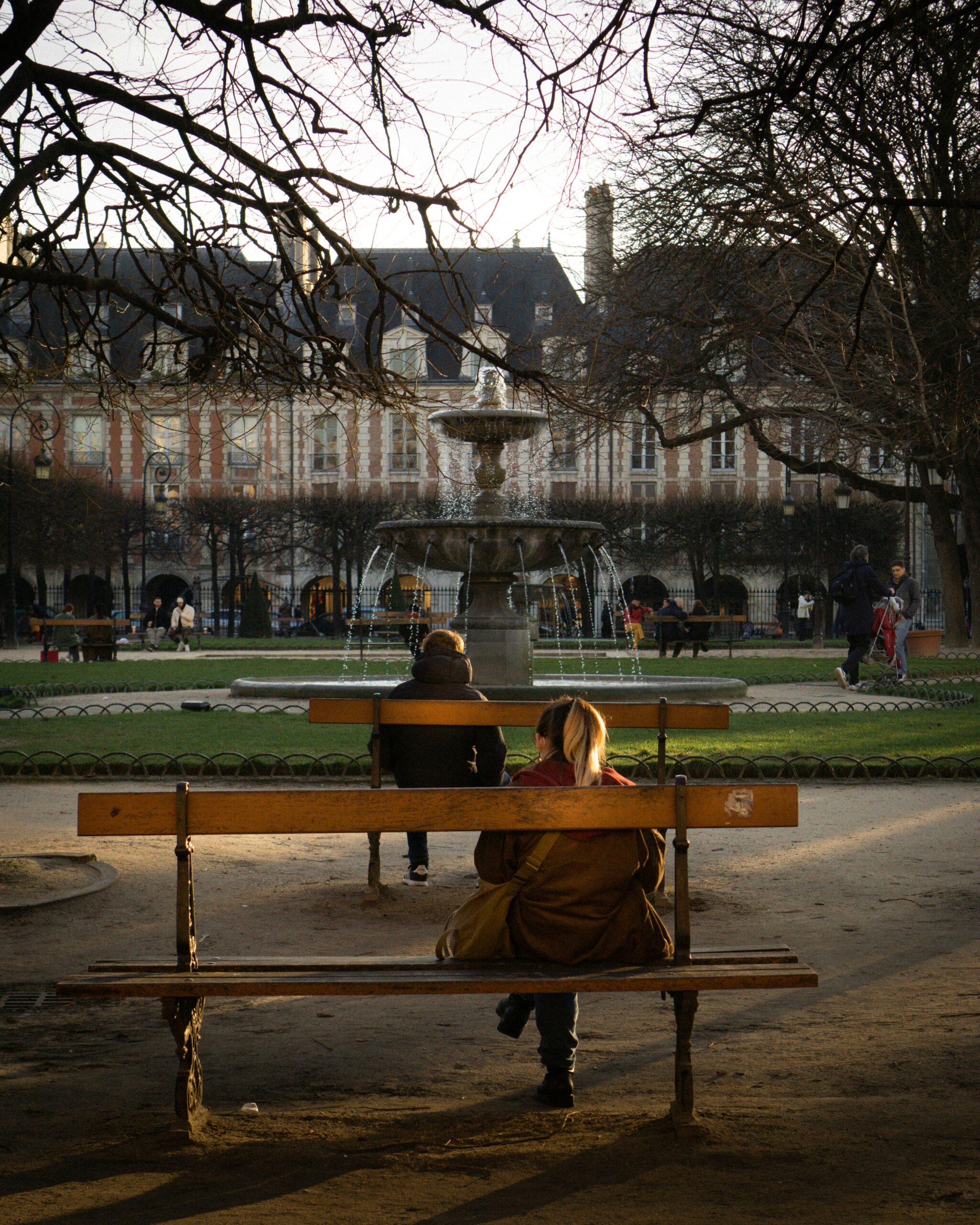 person sitting on a bench at Place des Vosges garden in Paris Le Marais