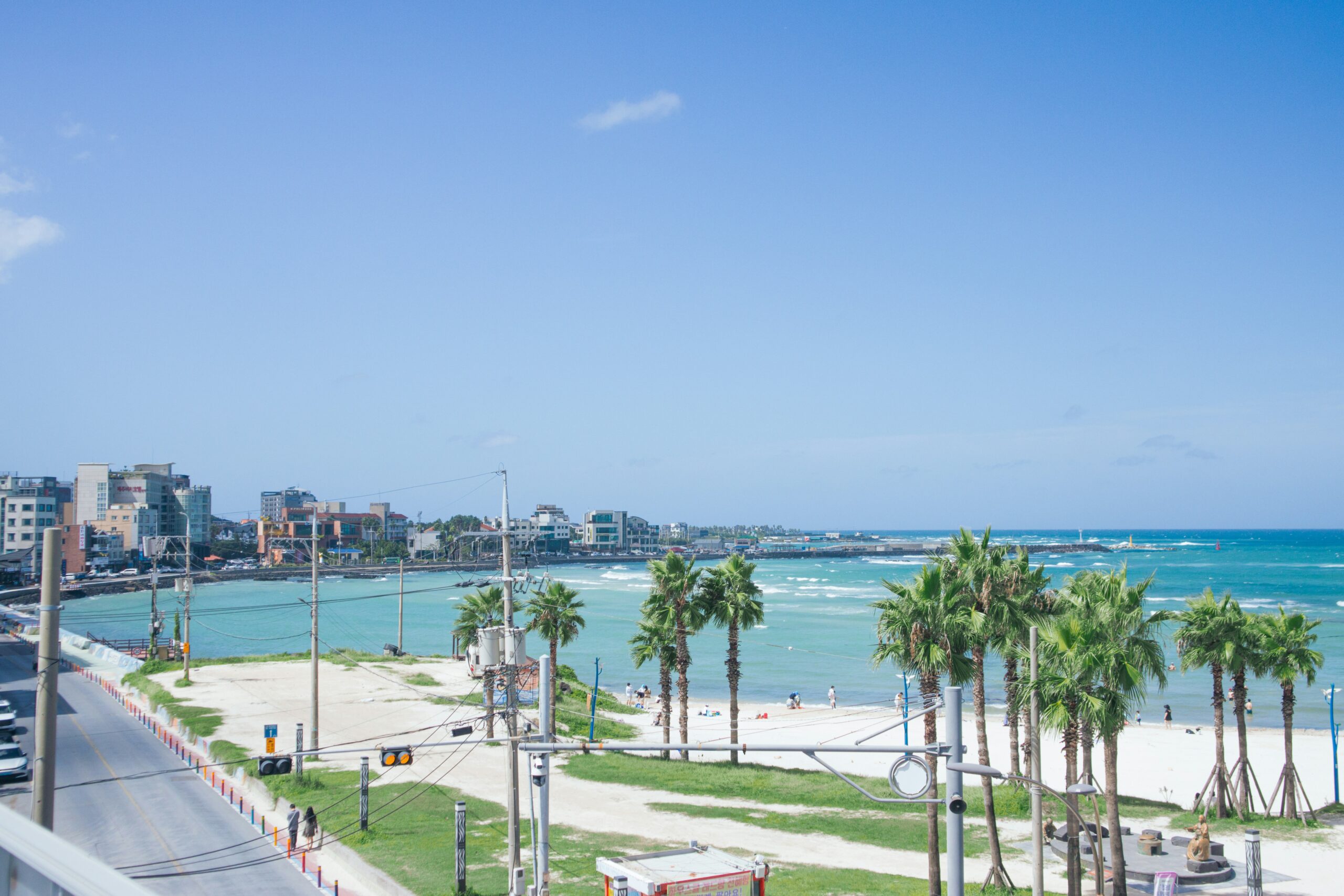 Hamdeok Beach Jeju with bright sand and turquoise shallow water in three curved bays