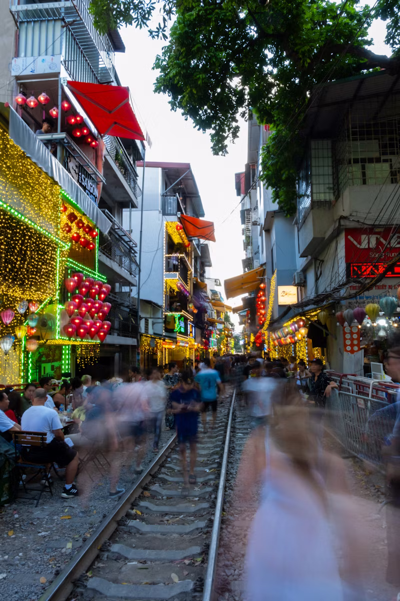 Hanoi Old Quarter street with train tracks, busy pedestrians, and vibrant local shops in Vietnam
