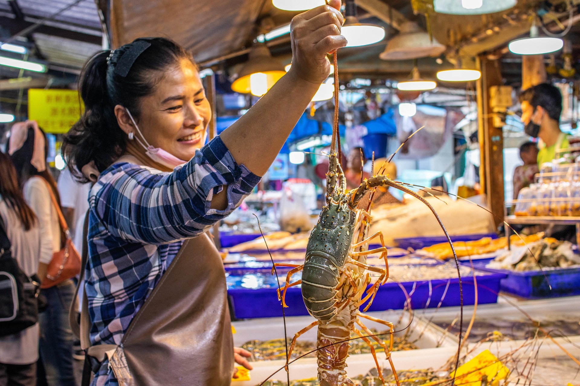 Chatuchak Market seafood vendor holding fresh lobster Bangkok Thailand