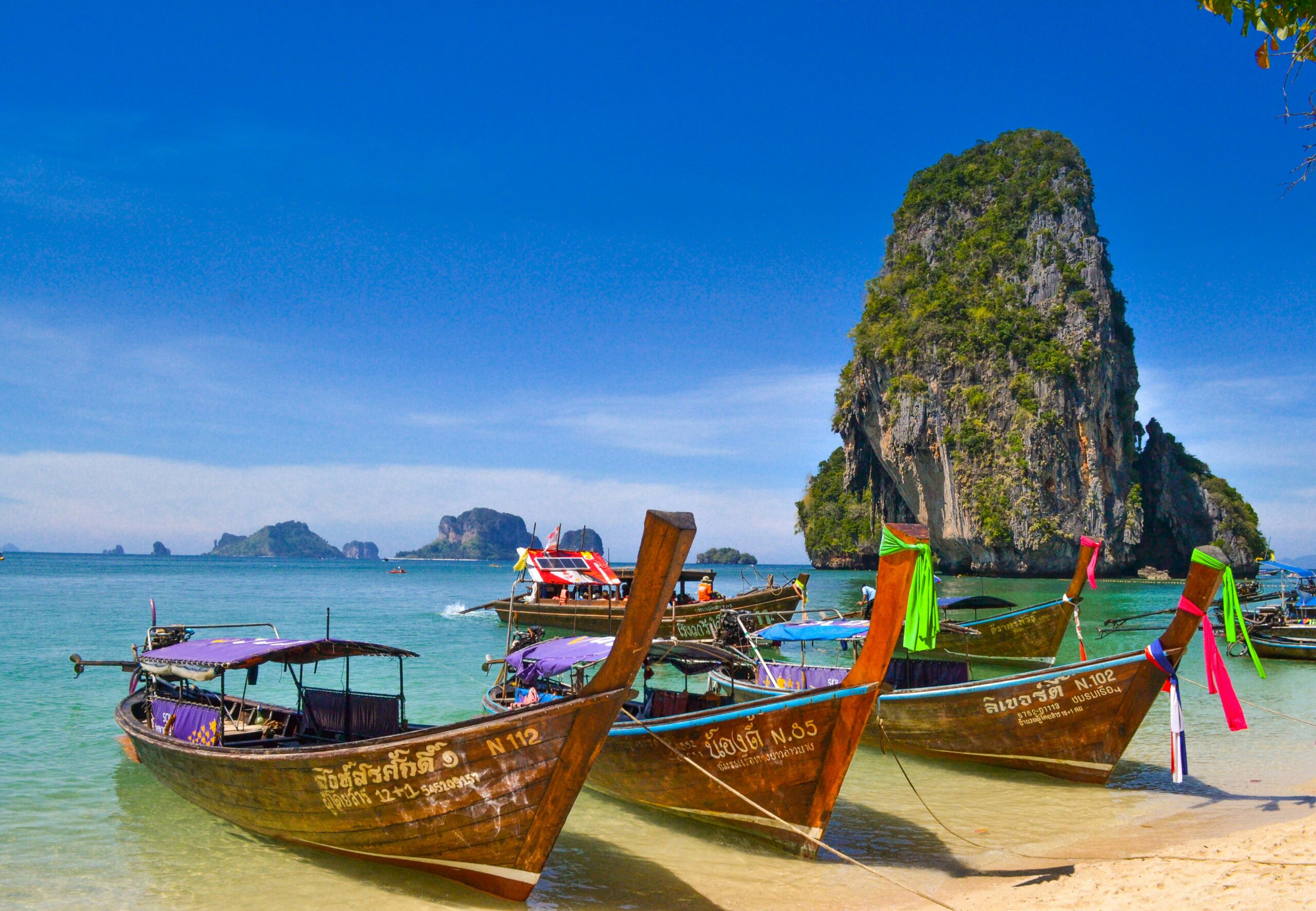 Thailand hidden destinations longtail boat tropical beach limestone cliffs clear water
